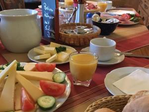 a table topped with plates of cheese and a glass of orange juice at Pension Schmiedeschänke in Dresden