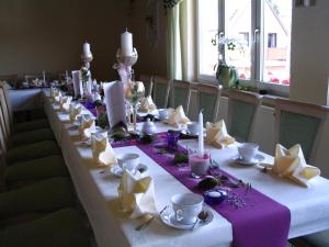 einem langen Tisch mit weißen und violetten Tafeln und Tassen in der Unterkunft Hotel Schöne Aussicht in Steinach