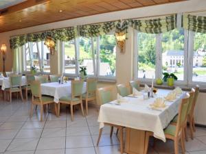 ein Restaurant mit weißen Tischen, Stühlen und Fenstern in der Unterkunft Hotel Schöne Aussicht in Steinach