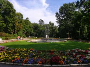 a park with a fountain and flowers in the grass at Lili in Arandjelovac