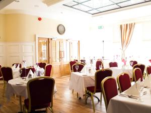 uma sala de jantar com mesas e cadeiras e um relógio em The Ryandale Inn em Dungannon