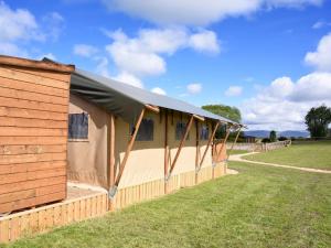 a building with a black roof on a grass field at Carr's Hill Luxury Safari Tents in Denny