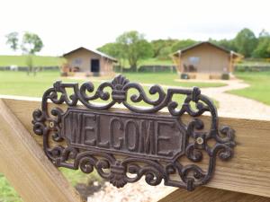 a metal sign on a wooden fence with a yard at Carr's Hill Luxury Safari Tents in Denny