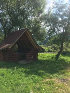 une petite cabane en rondins dans un champ d'herbe dans l'établissement Котедж біля річки, à Kelechin