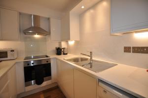 a kitchen with a sink, stove, microwave and refrigerator at Marlyn Lodge – City of London in London