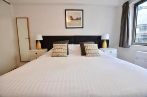 una camera da letto con un grande letto bianco con due lampade di Marlyn Lodge – City of London a Londra