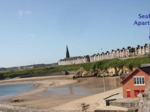 a view of a beach with a building on a cliff at Seafront Apartments in North Shields