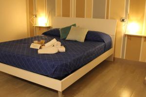ein Bett mit blauer Bettdecke und Schuhen darauf in der Unterkunft Sesta Strada in Civitavecchia