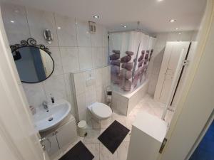 een badkamer met een wastafel, een toilet en een spiegel bij @ home Zimmervermietung in Norderstedt