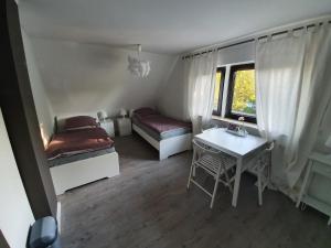 Cette chambre comprend 2 lits, une table et une fenêtre. dans l'établissement @ home Zimmervermietung, à Norderstedt