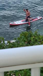 a man sitting on a paddle board in the water at Apartment Bonaca in Komarna