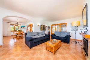a living room with two blue couches and a table at Villa Es Puig in S'Horta