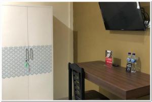 a room with a table and a tv on a wall at RedDoorz near RS Adam Malik Medan 2 in Sunggal