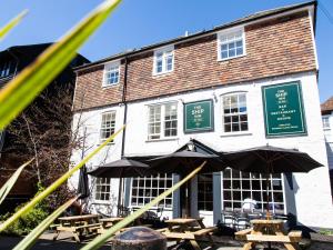 ein Gebäude mit Tischen und Sonnenschirmen davor in der Unterkunft The Ship Inn in Rye