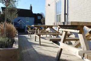 una fila de bancos de madera sentados junto a un edificio en The Ship Inn en Dymchurch