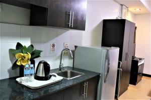 a kitchen with a sink and a refrigerator at The Studio 18 Residences in Manila