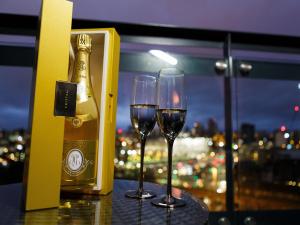two glasses of wine on a table with a bottle of champagne at Live in Leeds Sky Penthouse in Leeds