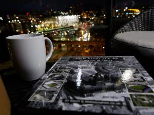 una tazza di caffè seduta su un tavolo accanto a una rivista di Live in Leeds Sky Penthouse a Leeds