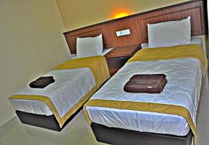 two beds in a hotel room with two bedsskirts at Tanjong Inn in Kota Bharu