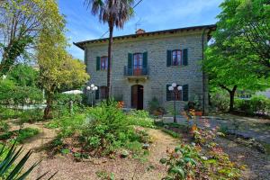 una casa de piedra con una palmera delante de ella en Villa Primula by PosarelliVillas, en Cortona