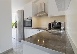 a white kitchen with a sink and a refrigerator at Apartments Goran by Rent Istria in Umag
