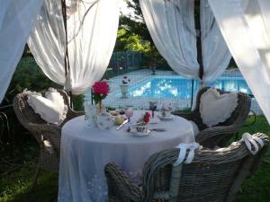 a table with a white table cloth and chairs and a pool at Le Moulin de Sonnailles in Cabriès