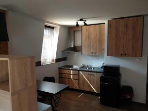 a kitchen with wooden cabinets and a table in it at Apartmány u Zbojnika Zabojnika in Bojnice