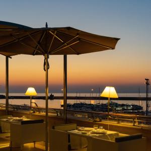 a beach area with tables, chairs and umbrellas at Palazzo del Corso – Boutique Hotel in Gallipoli