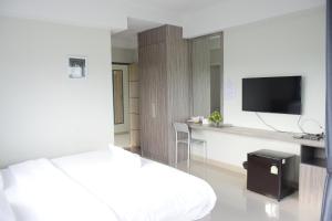 a bedroom with a bed and a desk with a tv at The grace kok udom in Prachin Buri