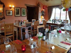 um restaurante com mesas e cadeiras com copos de vinho em The Oak Inn Staplow em Ledbury