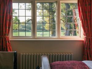 a room with three windows and a radiator in front at Oak House Farm in Edenbridge