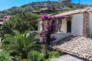 Una casa con flores púrpuras a un lado. en La Jacia Hotel & Resort en Baja Sardinia