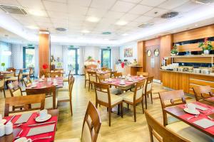 un ristorante con tavoli e sedie in legno e una cucina di ACHAT Hotel Budapest a Budapest
