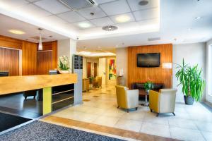 an office lobby with a desk and chairs and a tv at ACHAT Hotel Budapest in Budapest