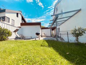 a house with a grassy yard next to a building at Modernes Apartment am Bodensee in Wasserburg