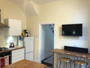 a kitchen with a refrigerator and a table with chairs at Sapphire House Sasco Apartments in Blackpool