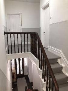 a staircase with white walls and brown railings at Sapphire House Sasco Apartments in Blackpool
