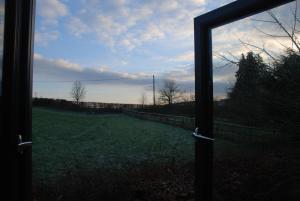 a view of a field through a glass window at Garden Studio Spring Cottage in Teffont Magna