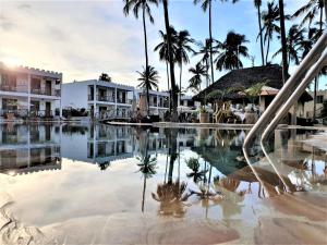 - une piscine dans un complexe avec des palmiers dans l'établissement Zanzibar Bay Resort & Spa, à Uroa