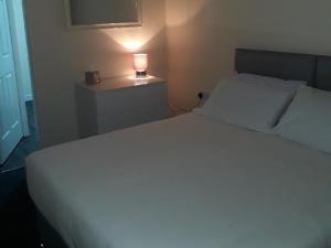 Un dormitorio con una cama blanca y una lámpara en una mesa en Stonefield Rooms, en High Blantyre