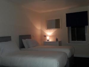 een hotelkamer met 2 bedden en een raam bij Stonefield Rooms in High Blantyre