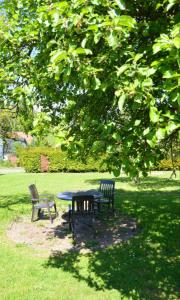 une table de pique-nique et deux chaises sous un arbre dans l'établissement Ferienwohnung Waldblick Bückeburg, à Bückeburg