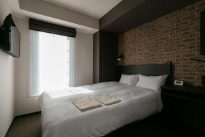 a bedroom with a white bed with two towels on it at HOTEL TABARD TOKYO in Tokyo