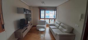 sala de estar con sofá y TV en Precioso apartamento en luanco junto a la playa, en Luanco