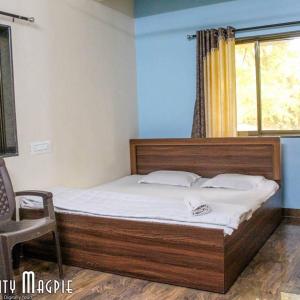 a bedroom with a bed and a chair and a window at Orchid Anant Holidays in Alibaug