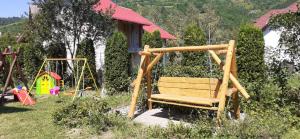 un parque infantil con banco de madera y columpio en Pensiunea Ando, en Bran