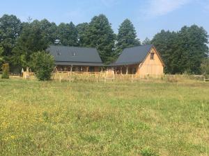 a large wooden barn in a field of grass at LEŚNE RANCZO AGROTURYSTYKA in Międzychód