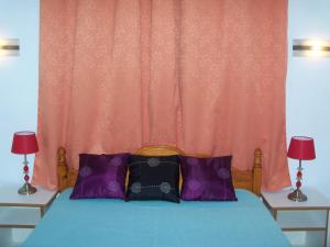 1 cama con almohadas moradas y cortina de color naranja en Villa Anse Goeland en Rodrigues Island