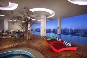 um quarto com piscina e uma árvore num edifício em ASTON Makassar Hotel & Convention Center em Macáçar