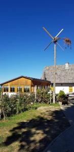 a building with a windmill in front of a house at Sobe, Rooms B&B - Vina Kauran in Zgornji Jakobski Dol